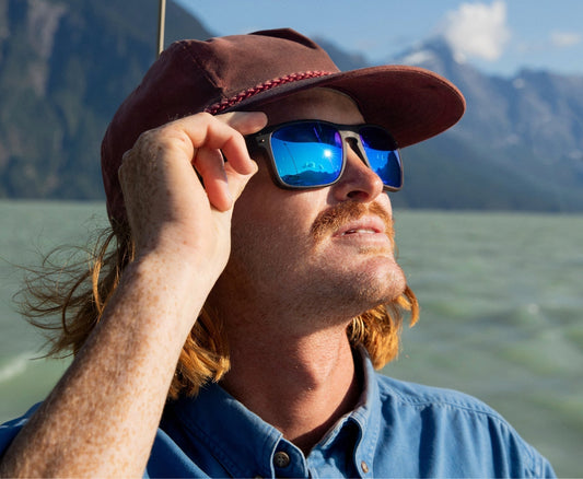 Image of a man on a boat wearing sunglasses with blue Revant Optics replacement lenses.