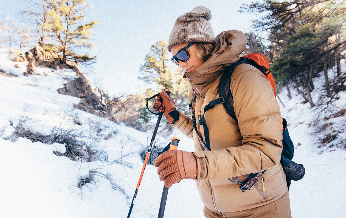 Hiking in snow with sunglasses on and dog on shoulders