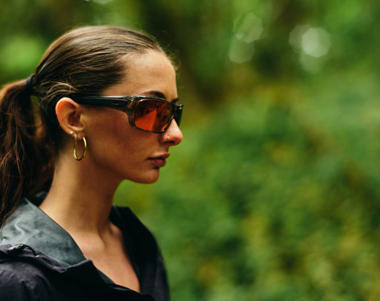 Image of a woman in a forest setting wearing sunglasses.