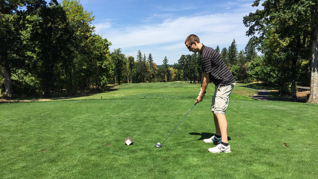 Man Teeing up to Drive a Golf Ball with Sunglasses On